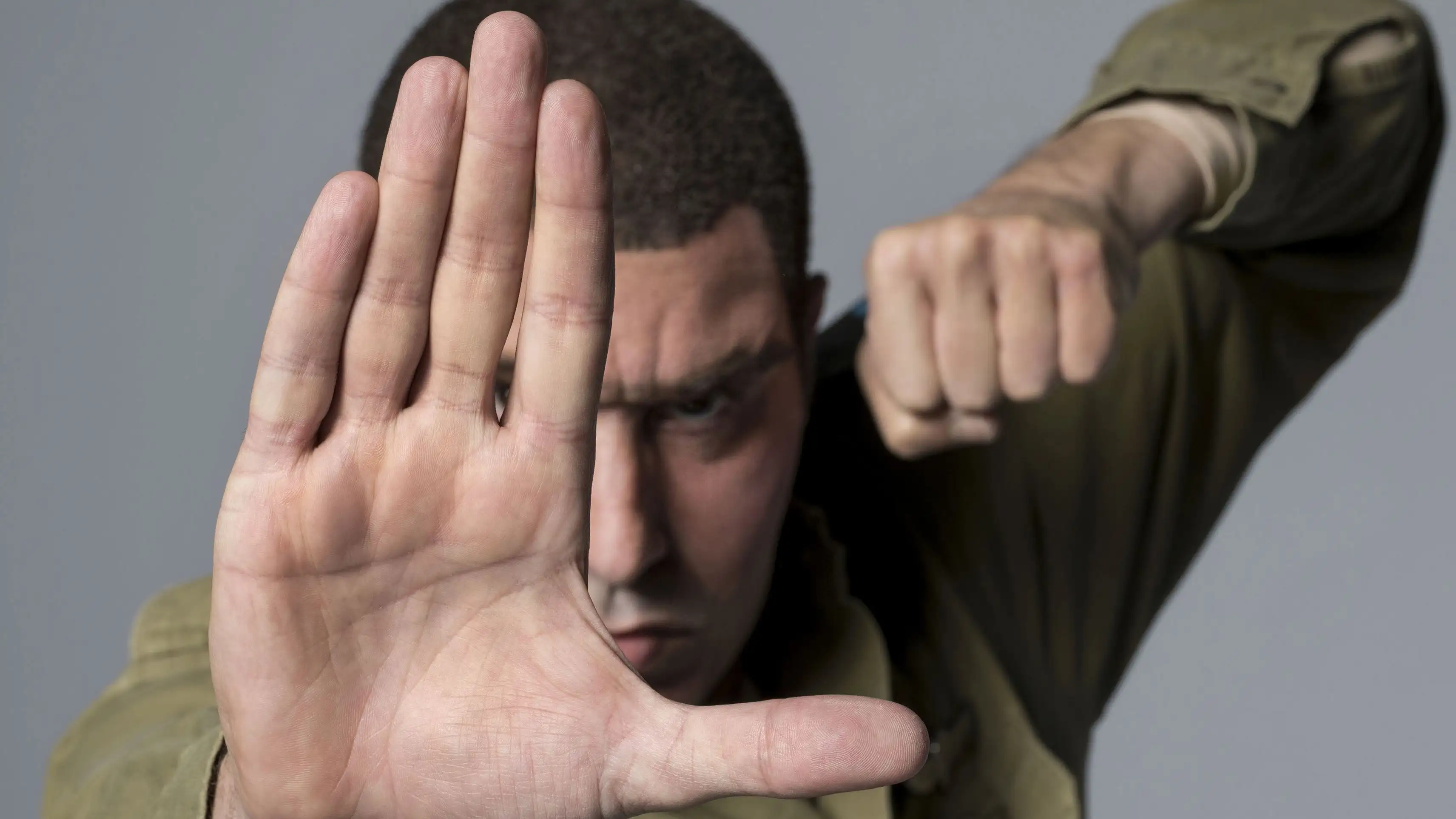 Sacha Baron Cohen as Colonel Erran Morad, in an olive shirt.